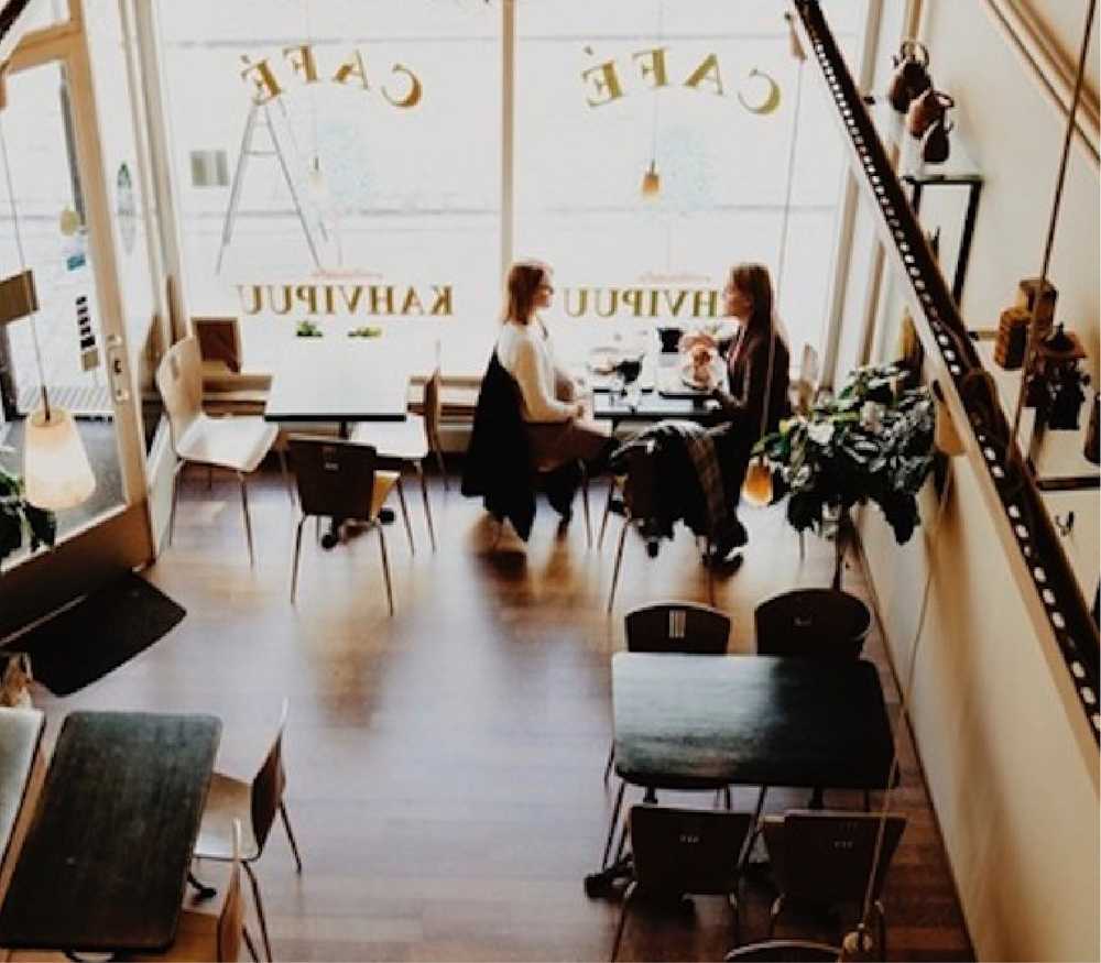 Two people sitting in a coffee shop talking over a few coffees.